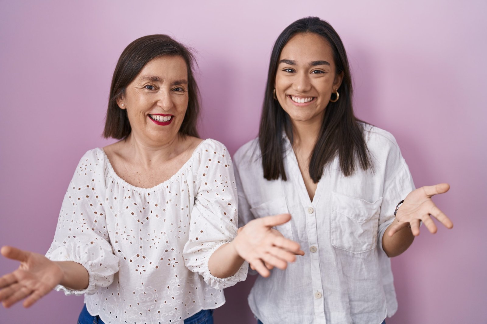 Hispanic mother and daughter together smiling cheerful with open arms as friendly welcome, positive and confident greetings